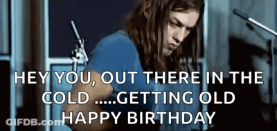 A Man With Long Hair Is Playing A Guitar In Front Of A Microphone In A Room . GIF