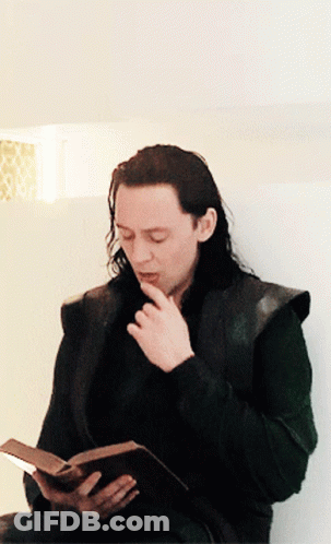 A Man With Long Hair Is Reading A Book While Sitting Down GIF