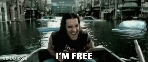 A Man With Long Hair Is Sitting In A Boat In A Flooded City . GIF