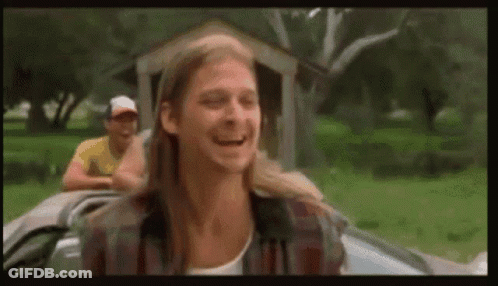 A Man With Long Hair Is Sitting In A Car Laughing . GIF
