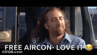 A Man With Long Hair Is Sitting In A Car With His Eyes Closed And Says `` Free Aircon - Love It '' . GIF