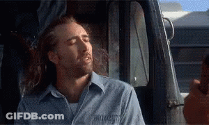 A Man With Long Hair Is Sitting In The Driver 'S Seat Of A Truck With His Eyes Closed . GIF