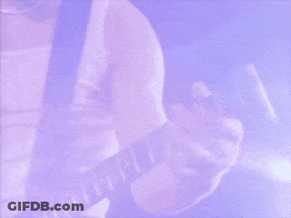 A Man With Long Hair Is Smiling And Looking At The Camera While Playing A Guitar . GIF