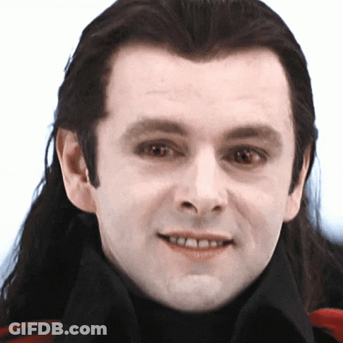 A Man With Long Hair Is Smiling And Wearing A Black Turtleneck GIF