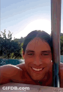 A Man With Long Hair Is Smiling In A Swimming Pool GIF