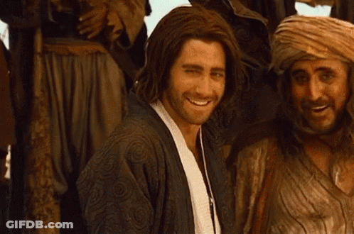 A Man With Long Hair Is Smiling In Front Of A Group Of People GIF