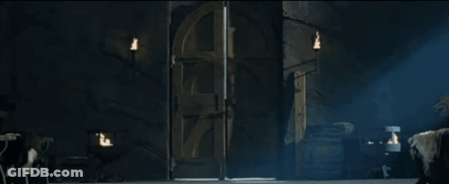 A Man With Long Hair Is Standing In A Dark Room Holding A Door Open GIF