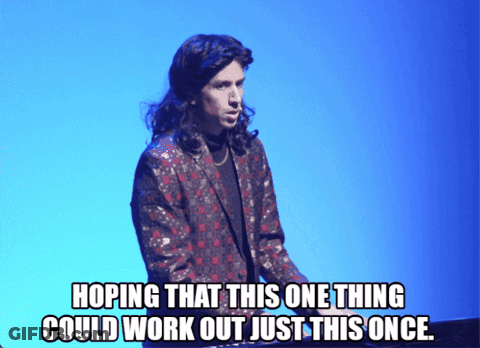 Long-Haired Man Standing In Front Of Blue Background Hoping For Something GIF