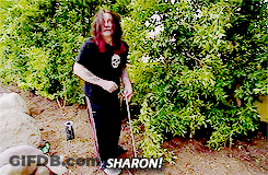 A Man With Long Hair Is Standing In Front Of A Bush With Sharon Written On The Bottom GIF