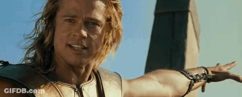 A Man With Long Hair Is Standing In Front Of A Tower With His Arm Outstretched . GIF