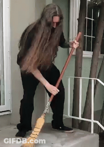 A Man With Long Hair Is Sweeping The Floor With A Broom GIF
