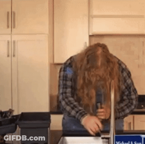 A Man With Long Hair Is Washing His Hands In A Sink . GIF