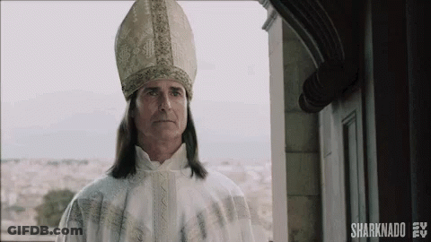 A Man With Long Hair Is Wearing A Bishop 'S Hat And Robe . GIF