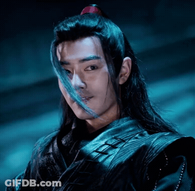 A Man With Long Hair Is Wearing A Black Jacket And Has A Red Ponytail . GIF