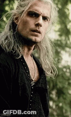 A Man With Long Hair Is Wearing A Black Shirt And A Necklace . GIF