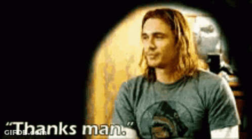 A Man With Long Hair Is Wearing A Gray Shirt And Says Thanks Man . GIF