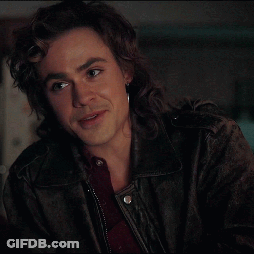 A Man With Long Hair Is Wearing A Leather Jacket And Earrings GIF