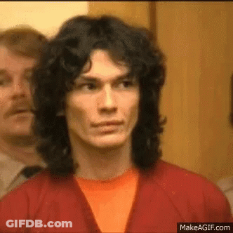 A Man With Long Hair Is Wearing A Red Jacket And An Orange Shirt . GIF