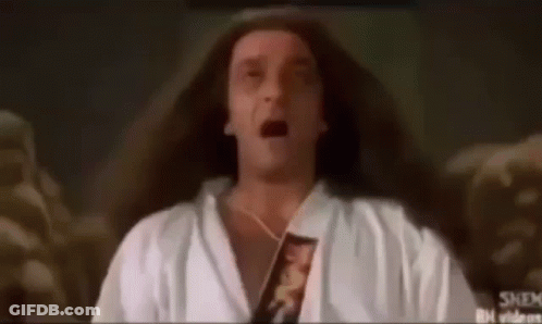 A Man With Long Hair Is Wearing A White Robe And Holding A Book In His Hand . GIF