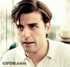 A Man With Long Hair Is Wearing A White Shirt And Looking At The Camera . GIF
