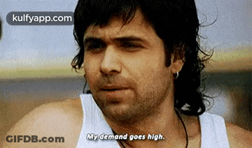 A Man With Long Hair Is Wearing A White Tank Top And Earrings . GIF