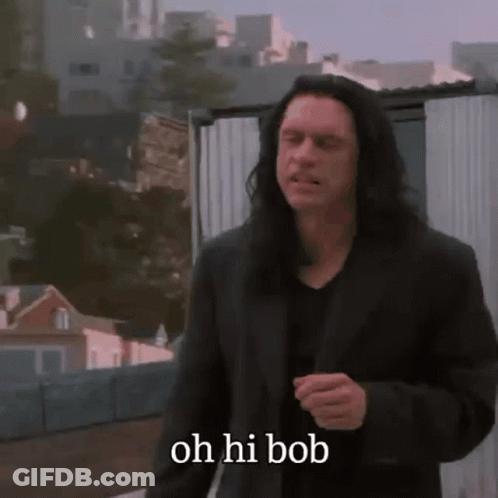 A Man With Long Hair Says Oh Hi Bob While Walking Down A Street GIF