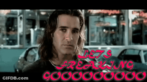A Man With Long Hair Stands In Front Of A Sign That Says " Let 'S Freaking Gooooo " GIF