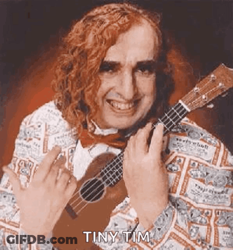 A Man With Long Red Hair Is Holding A Guitar And Smiling . GIF