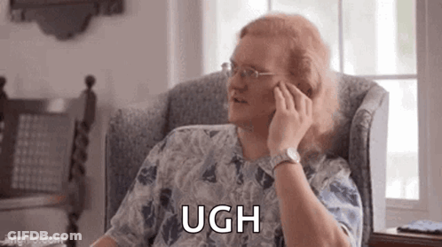 A Man With Long Red Hair Is Sitting In A Chair Talking On A Cell Phone . GIF