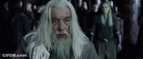 A Man With Long White Hair And A Beard Is Looking At The Camera GIF