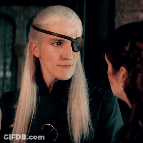 A Man With Long White Hair And An Eye Patch On His Forehead Looks At A Woman GIF