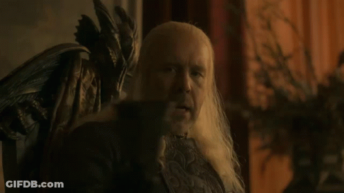 A Man With Long White Hair Is Sitting In A Chair With The Word Wine Below Him GIF
