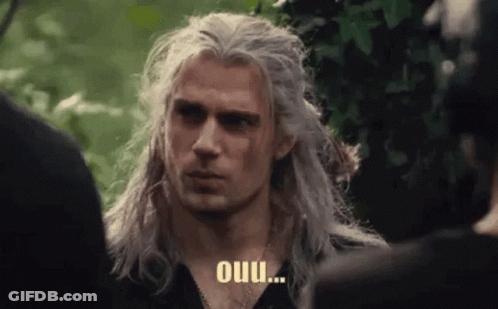 A Man With Long White Hair Is Standing In Front Of A Group Of People And Talking To Them . GIF