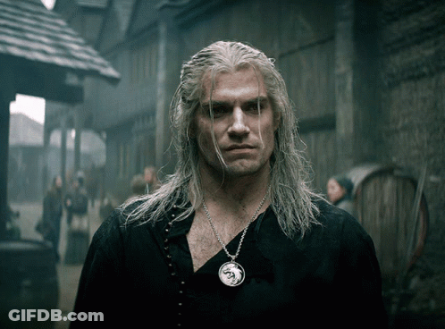 A Man With Long White Hair Is Wearing A Necklace With A Dragon Pendant GIF
