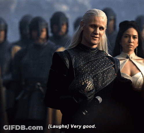 A Man With Long White Hair Says [ Laughs ] Very Good In Front Of A Group Of People GIF