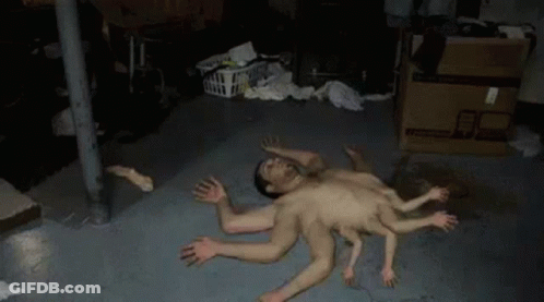 A Man With Many Hands Is Laying On The Floor In A Basement . GIF