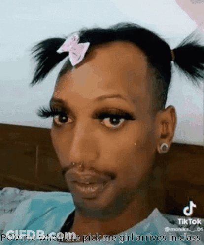 A Man With Pigtails And A Pink Bow On His Head Is Wearing Makeup . GIF
