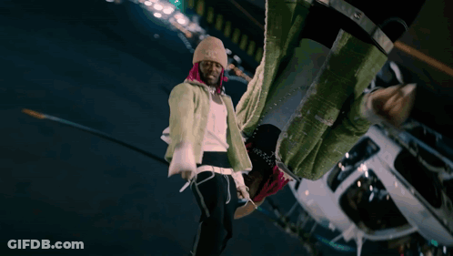 A Man With Pink Hair And A Beanie Stands In Front Of A White Helicopter GIF