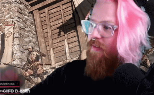 A Man With Pink Hair And Glasses Looks At The Camera GIF