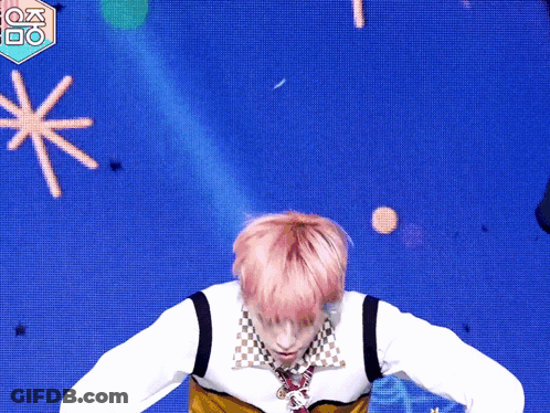 A Man With Pink Hair Is Dancing In Front Of A Blue Background With A Fox Logo GIF