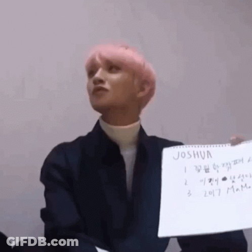A Man With Pink Hair Is Holding A Piece Of Paper That Says Joshua . GIF