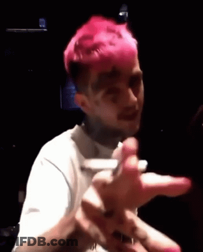 A Man With Pink Hair Is Making A Funny Face While Holding A Cell Phone In A Dark Room . GIF