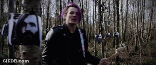 A Man With Pink Hair Is Playing A Guitar In A Forest GIF