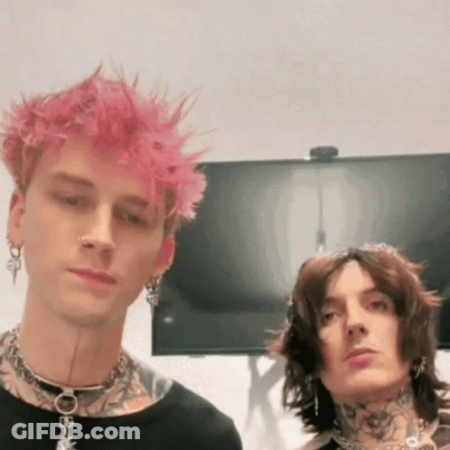 A Man With Pink Hair Is Standing Next To Another Man With Black Hair And Tattoos . GIF