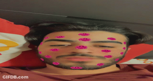 A Man With Pink Smiley Faces On His Face Laying On A Bed GIF