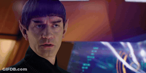 A Man With Purple Hair And Ears Is Standing In Front Of A Computer Screen GIF