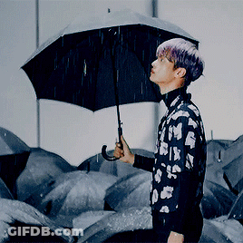 A Man With Purple Hair Is Holding A Black Umbrella GIF