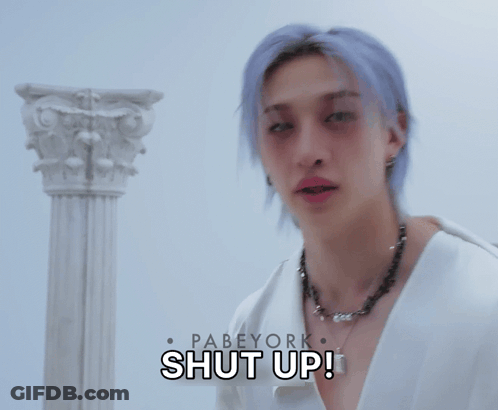 A Man With Purple Hair Is Holding A Hammer In Front Of A Sign That Says " Shut Up " GIF