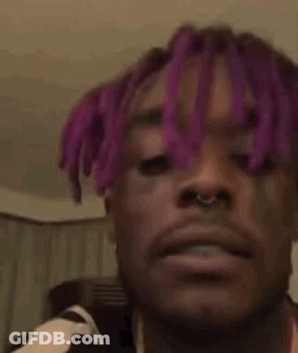 A Man With Purple Hair Is Making A Funny Face . GIF