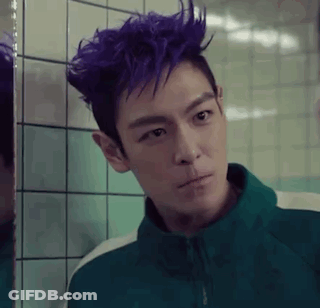 A Man With Purple Hair Is Standing In Front Of A Mirror . GIF